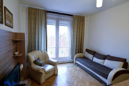 a living room with a couch and a chair and a tv at City Center Apartment in Debrecen
