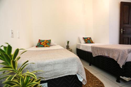 a room with two beds and a potted plant at Pousada Movimento in Prea