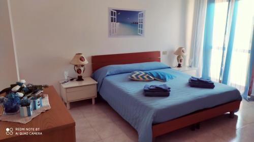 um quarto com uma cama com lençóis azuis e uma mesa em By Azzurra Tra Mare e Montagna em Sìnnai