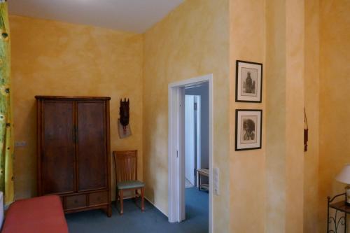 a room with yellow walls and a cabinet and a chair at Landhaus Schloss Kölzow in Kölzow