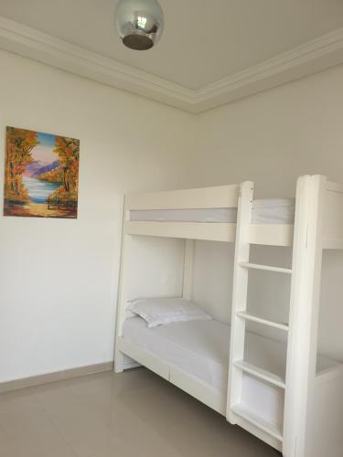 席迪拉罕的住宿－Appartement Ola Blanca 2，一间带白色双层床的卧室和一幅画