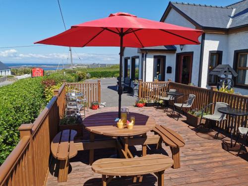 a wooden deck with a table with a red umbrella at Ocean Heights B&B in Lissadell