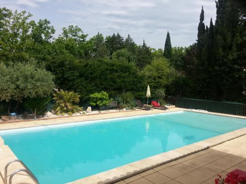 a large blue swimming pool with trees in the background at La Combe Joseph in Remoulins