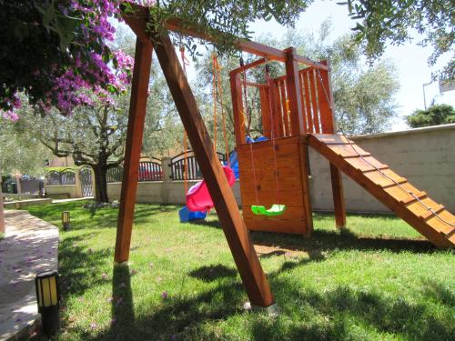 a wooden playground with a slide in the grass at Apartments Irena with sea view in Fažana