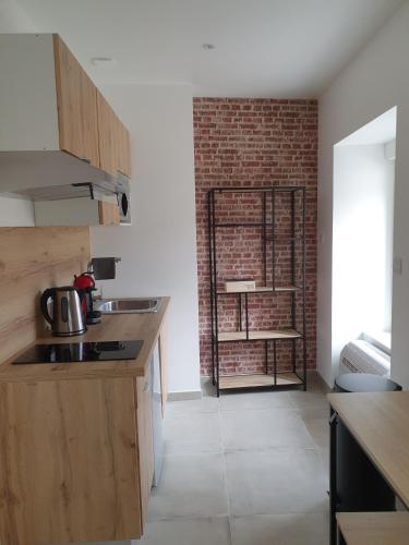 uma cozinha com armários de madeira e uma parede de tijolos em Les Suites du Relais em Saint-Martin-dʼAblois