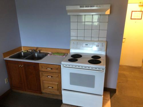 a kitchen with a white stove and a sink at Travel Inn & Suites in Innisfail