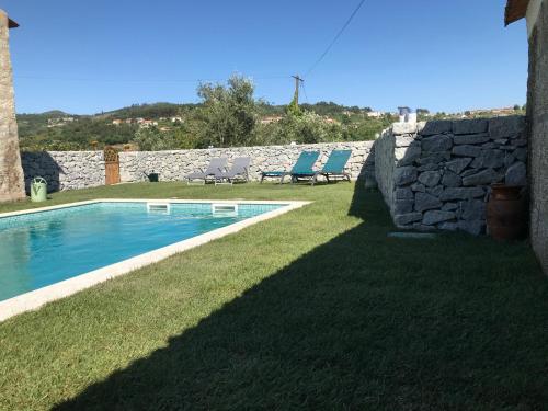 a yard with a swimming pool and a stone wall at Casa da Ponte in Baião