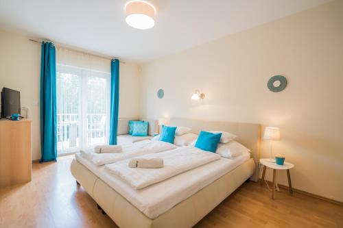 duże białe łóżko z niebieskimi poduszkami w sypialni w obiekcie Villa Frida w Siófoku
