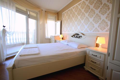 sypialnia z łóżkiem z 2 lampami i oknem w obiekcie Villa Livia Boutique Apartments w Rawdzie