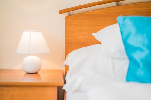 a white lamp sitting on a table next to a bed at Villa Frida in Siófok