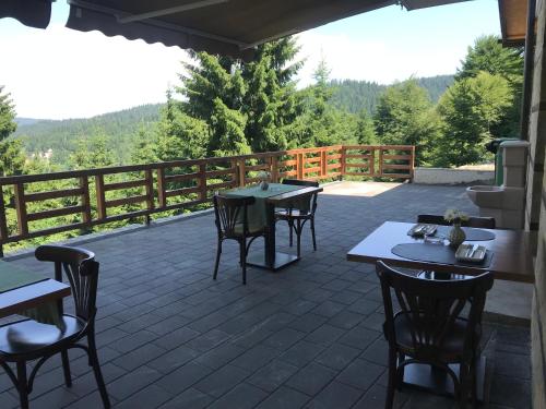 eine Terrasse mit Tischen, Stühlen und einem Zaun in der Unterkunft Vila Lucky Kop & Restoran in Kopaonik