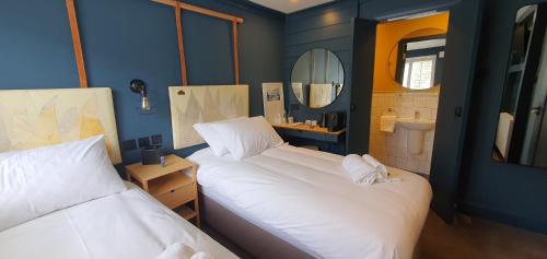a room with two beds and a bathroom with a mirror at The Lemon Leaf Café Bar and Townhouse in Kinsale