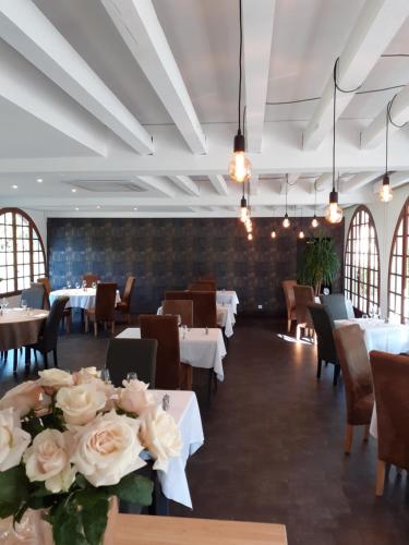 une salle à manger avec des tables, des chaises et des fleurs dans l'établissement L'Auberge, à Saint-Viance