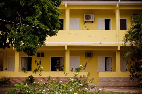Pousada Pau Brasil في إلها دي كومانداتوبا: مبنى أصفر بأبواب ونوافذ بيضاء