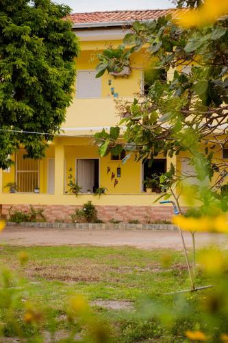 a yellow house is seen through the trees at Pousada Pau Brasil in Ilha de Comandatuba