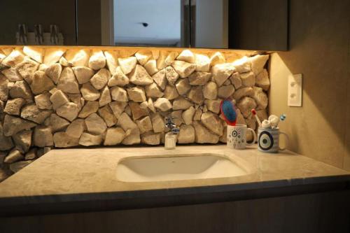 a bathroom counter with a sink and a stone wall at ILE DE PIPA LUXO in Pipa