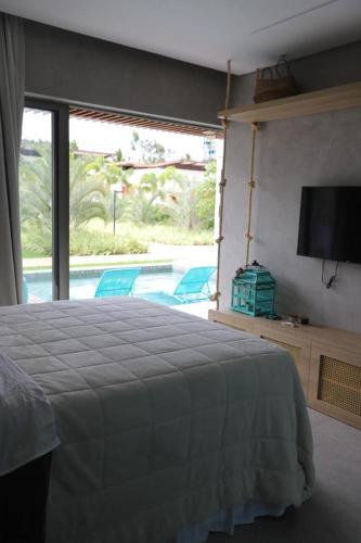 a bedroom with a bed and a tv and a pool at ILE DE PIPA LUXO in Pipa