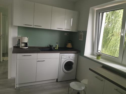 uma cozinha branca com uma máquina de lavar roupa e uma janela em Thüringer Panorama em Gossel