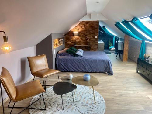 a bedroom with a bed and two chairs and a table at Ferme "les Flaquettes" in Guînes