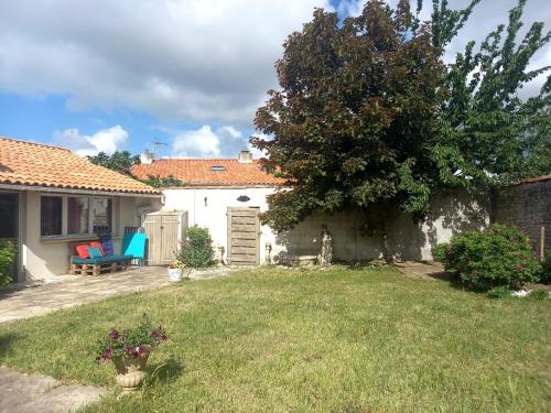 uma casa com um quintal com um banco e uma árvore em Chez Chris em Jard-sur-Mer