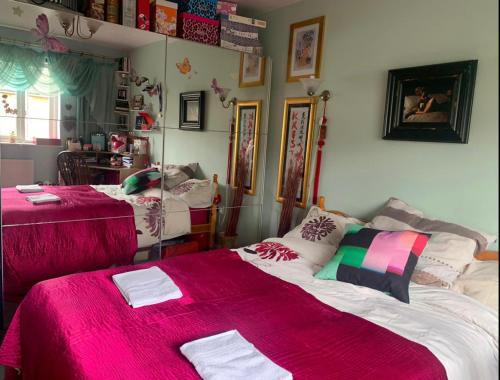 a bedroom with two beds with pink blankets at Cosy room in London Wembley in London