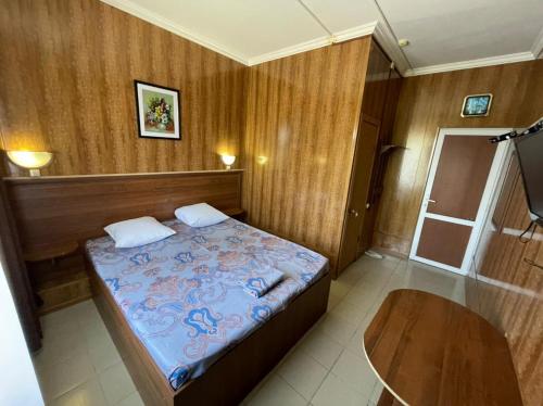 a small bedroom with a bed and a table at Гостиница Глория in Pyatigorsk