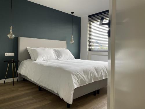 a bedroom with a bed with white sheets and a window at N9 Texel in De Koog