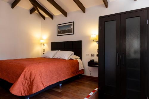a bedroom with a bed and a black wardrobe at Hostal & Apartments El Triunfo in Cusco