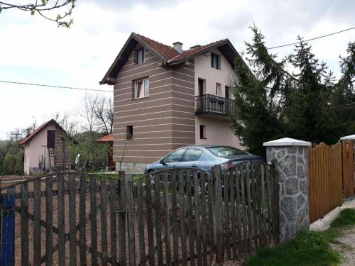 茲拉蒂博爾的住宿－Zlatiborska seoska idila，前面有栅栏和汽车的房子