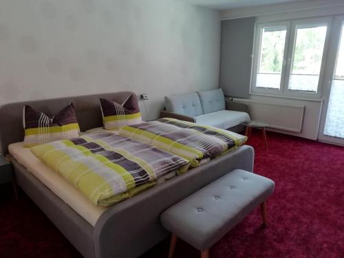 een slaapkamer met een bed, een bank en een stoel bij Couple Appartement Pension Volgenandt in Breitenbach