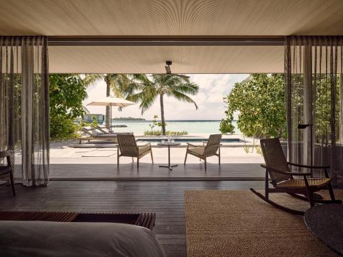 a bedroom with a view of the ocean from a resort at Patina Maldives, Fari Islands in North Male Atoll