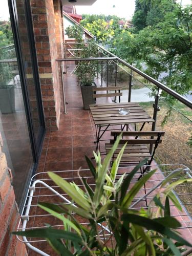 a balcony with a wooden table and benches on it at Castellum Apartmanház in Gyula