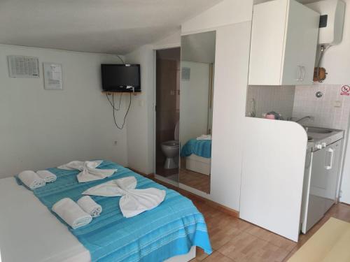 - une chambre avec un lit bleu et des serviettes dans l'établissement Apartments Mirjana, à Makarska