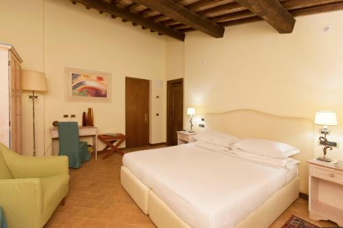 a bedroom with a large white bed and a desk at Sovana Hotel & Resort in Sovana