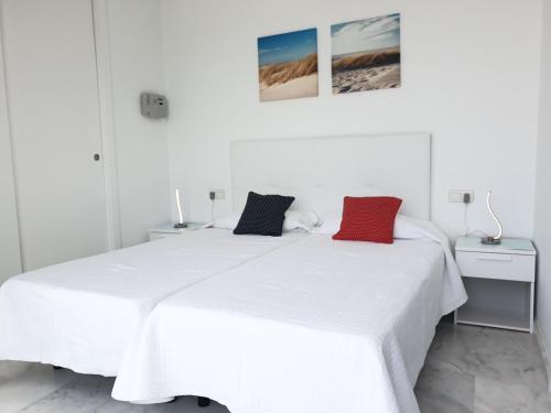 2 camas en un dormitorio blanco con almohadas rojas y negras en Breathtaking sea views apartment with private terrace 146 en Benidorm