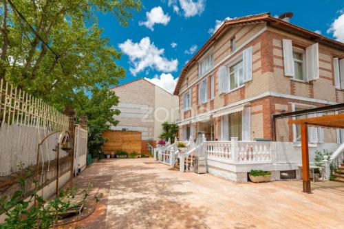 a brick house with a white fence and a driveway at Hotel Rural Mansión in Navalcarnero