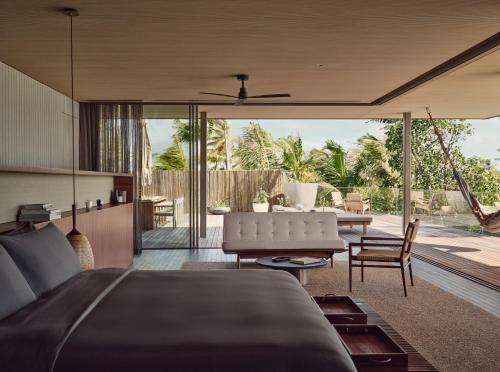 a bedroom with a bed and a living room at Patina Maldives, Fari Islands in North Male Atoll