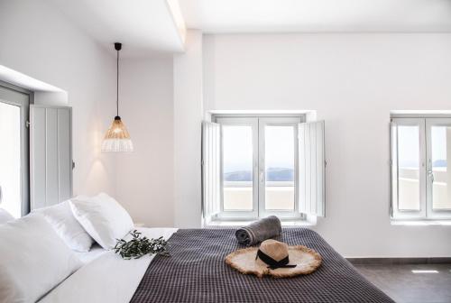 a bedroom with a bed with a hat on it at Caldera Cliff Illusion in Fira