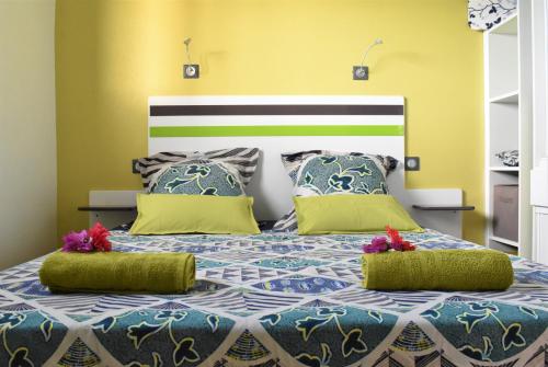 um quarto com uma cama grande e 2 almofadas verdes e azuis em Creole Nest em Pointe-Noire