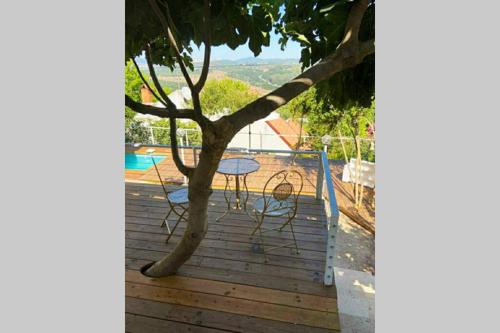 a table and chairs on a deck with a tree at היחידה - Hayehida in Ma'alot Tarshiha