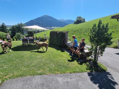 a group of people sitting on a bench with sheep at Appartment Sattlerhof in Mutters