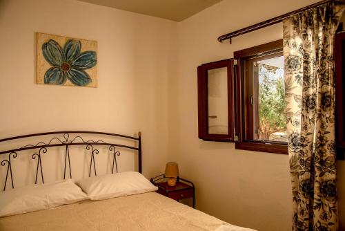1 dormitorio con cama y ventana en flamingo colour valey house, en Palaikastro
