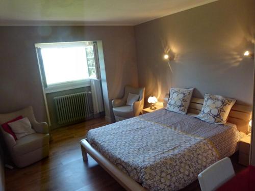 a bedroom with a bed and two chairs and a window at Chambres d'Hôtes Baudelys in Pont-de-Larn