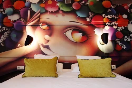 a bedroom with a painting of a face with glasses at Hôtel la Capelle Millau in Millau