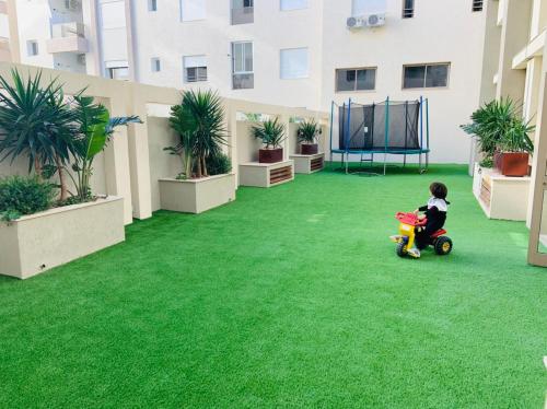 a small child riding a toy on a lawn at APPARTEMENT PARADISIAQUE entre HAMMAMET et NABEUL in Nabeul