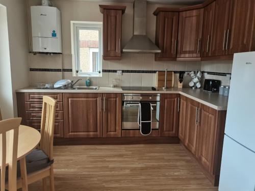 a kitchen with wooden cabinets and a stove top oven at No2 Glan Nodwydd in Pentraeth