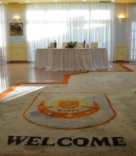 a welcome rug in the middle of a room with a table at Hotel Sunce Sarajevo Vogosca in Vogošća