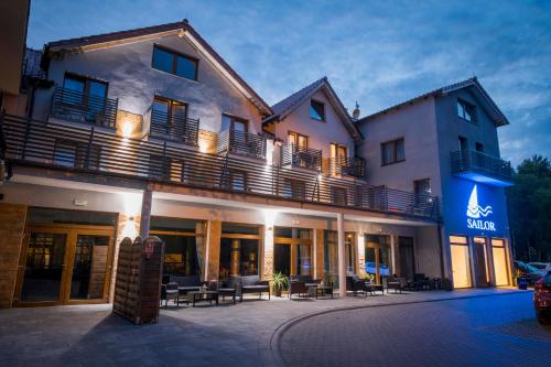 a hotel with tables and chairs in front of it at Sailor Łeba in Łeba