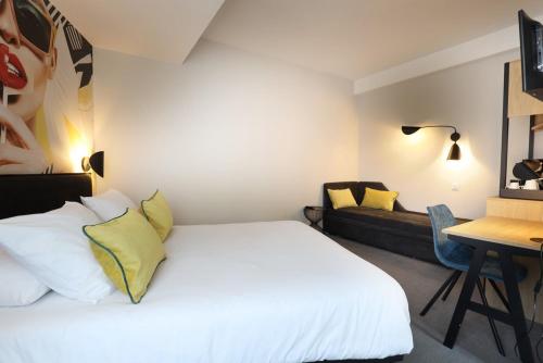 a bedroom with a white bed and a couch at Hôtel la Capelle Millau in Millau