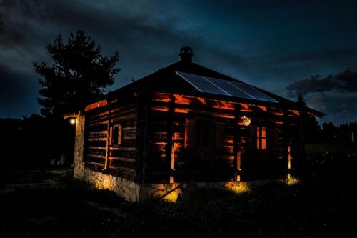 an old log cabin lit up at night at Збориште in Brdo